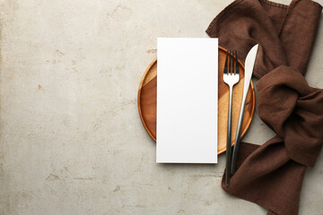 Wall Mural - Empty menu, plate, cutlery and napkin on light grey table, top view. Mockup for design