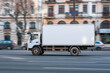 © Centric  - A white delivery truck moving along a busy city street, illustrating urban logistics and transportation