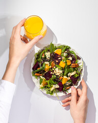 Wall Mural - Woman with salad and orange juice sitting at white table