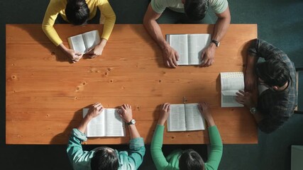 Wall Mural - Top view of prayer hold each other support while prays to god at table with bible and cross placed with faith, spirituality and religion. Aerial view of diverse people holding and praying. Symposium.