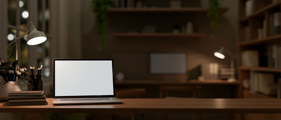 Wall Mural - a front view image of a laptop computer mockup on a wooden table in a dark office.