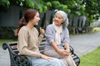 © bongkarn - A lovely Asian granddaughter and a happy grandma are enjoying a conversation in a park together.