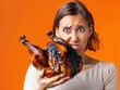 © tantawat - Holiday Disaster - Woman Holding Burnt Thanksgiving Turkey with Exasperated Look in Bright Orange Background
