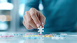 © TH_Stock - Close-up of a person's hand placing a white puzzle piece onto a table filled with colorful pieces. The scene emphasizes strategy, problem-solving, and the process of completing a puzzle.