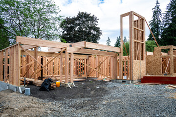Wall Mural - New house construction in residential neighborhood, job site exterior, wood house framing started, piles of delivered lumber and assorted small materials, ready for the workmen
