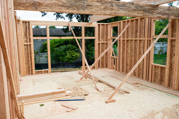 Wall Mural - New house construction in residential neighborhood, job site detail looking through window opening to subfloor and wood framed walls supported by crossed 2x4s 
