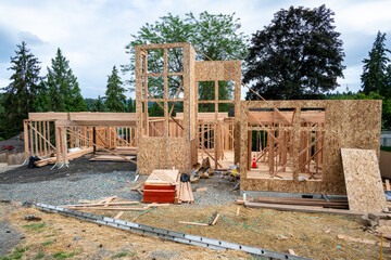 Wall Mural - New house construction in residential neighborhood, job site full view, wood house framing started, piles of delivered lumber, extension ladder, assorted small materials, ready for the workmen
