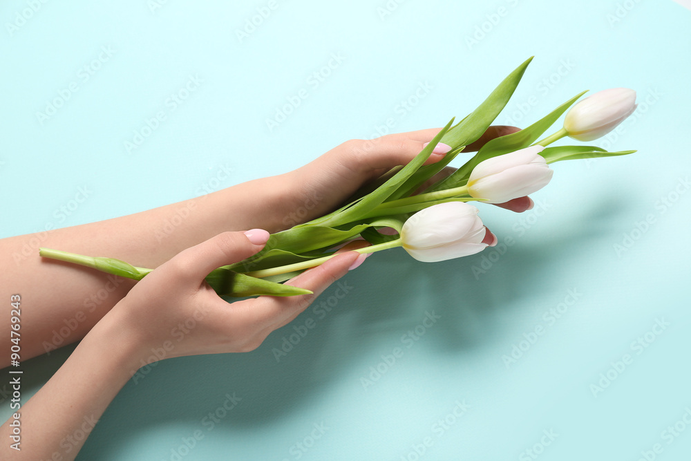 Woman with white tulips on blue background. Hand care concept
