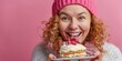 © Boomanoid - Smiling Woman in Pink Beanie Enjoying a Delicious Cake with Cream and Berries