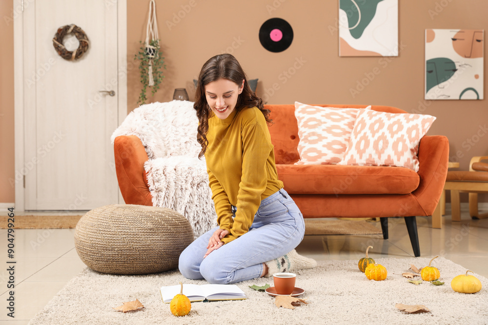 Young woman reading book at home on autumn day