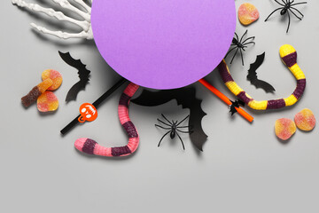 Wall Mural - Composition with blank card, sweet candies and Halloween decorations on grey background, closeup