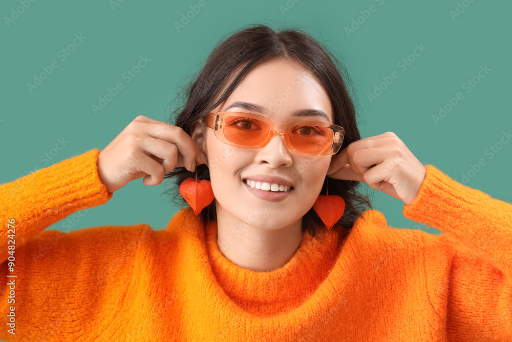 Young Asian woman with physalis on green background, closeup