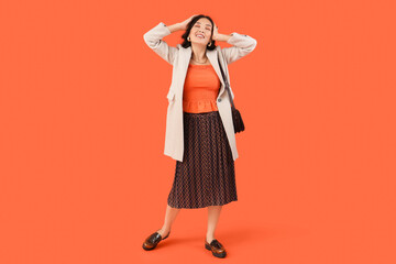 Poster - Stylish young Asian woman in fall clothes on red background