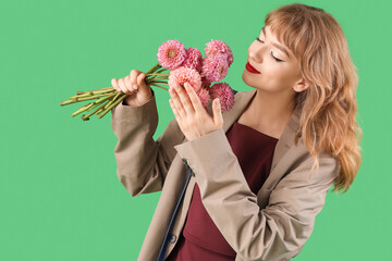 Poster - Stylish young woman in fall clothes with flowers on green background