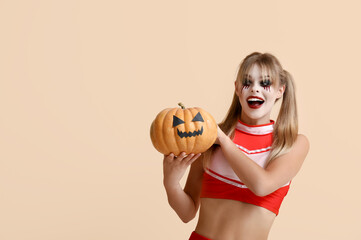 Wall Mural - Young woman dressed for Halloween as cheerleader with pumpkin on beige background