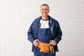 Sticker - Portrait of male mechanic with tool belt on white brick background