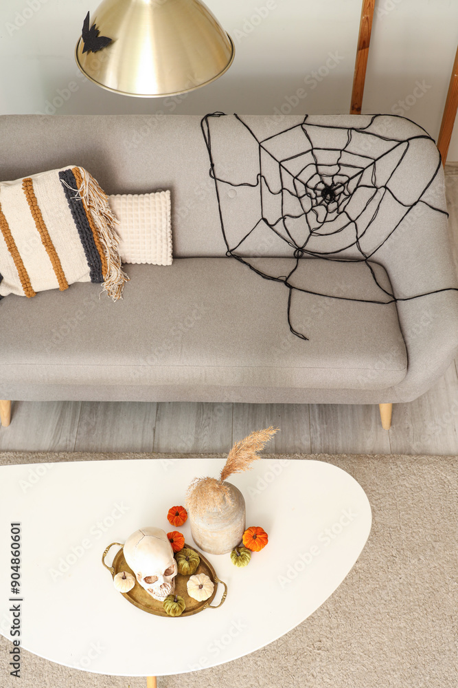 Interior of light living room decorated for Halloween with sofa and table