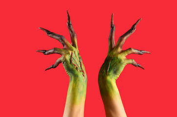 Wall Mural - Hands of witch with claws on red background. Halloween celebration