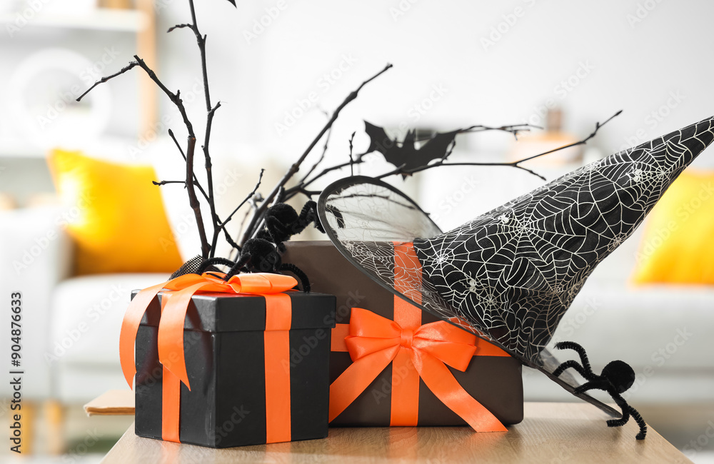 Coffee table with Halloween gift boxes, witch hat and spiders in living room, closeup