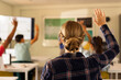 © wavebreak3 - In high school, students raising hands in classroom, actively participating in lesson