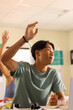 © wavebreak3 - In high school, teenage boy raising hand in classroom, participating in lesson
