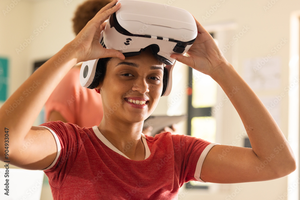 Using VR headset, smiling teenager in high school classroom, enjoying ...