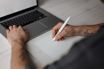 Young professional male designer sitting in office and drawing on tablet