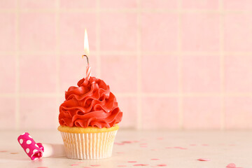 Wall Mural - Sweet Birthday cupcake with burning candle and party whistle on white table