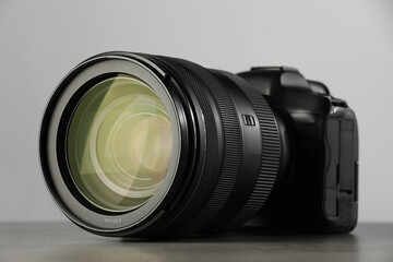 Wall Mural - Modern photo camera on grey table, closeup. Photographer's equipment