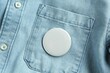 © New Africa - White button badge pinned on denim shirt, top view. Mockup for design