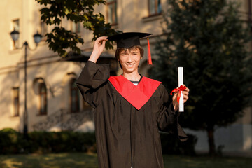 Canvas Print - Happy male graduating student with diploma outdoors