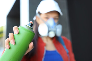 Poster - Young woman in respirator with spray paint can on street, closeup