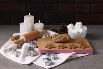 Wall Mural - Raw dough, cookie cutters, pine cones, marshmallows, rolling pin and burning candles on grey table