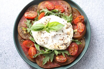 Wall Mural - Delicious fresh burrata salad in bowl on light gray textured table, top view