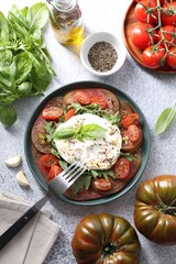 Wall Mural - Delicious fresh burrata salad in bowl served on light gray textured table, flat lay