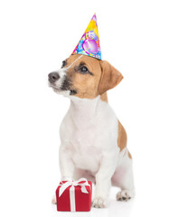 Aufkleber - Cute Jack russell terrier puppy wearing party cap sits with gift box and looks up on empty space. isolated on white background