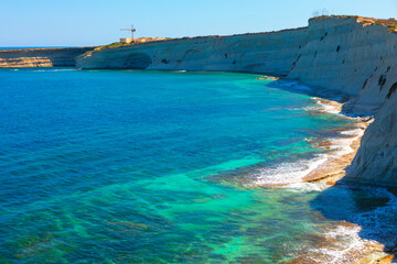 Wall Mural - View of the coast of the island of Malta. Sea is calm and blue, with a rocky shoreline in the background. The water is clear and the waves are gentle