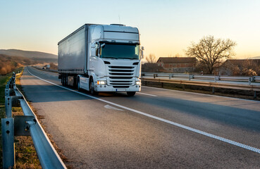 Wall Mural - 
Big white semi trailer truck on a highway driving at bright sunny sunset. Transportation vehicle

