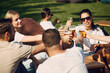© master1305 - Joyful gathering. Group of friends, men and women sitting outdoors in restaurant, talking, laughing and drinking refreshing beer. Concept of summer, leisure, friendship, meeting, fun, relaxation