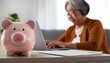 © LL - Toy pink piggy bank on work table of senior tenant, homeowner woman. Elderly lady using calculator, counting savings, taxes. Finance management, financial insurance