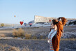 © VICHIZH - Serene woman enjoys scenic view of colorful hot air balloons floating in a vast field