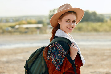 Wall Mural - serene woman in field with sunlight, hat, and backpack