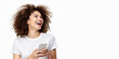 © Shyla Marsare - Mujer feliz sujetando un smartphone. Mujer afro riendo con camiseta blanca. Chica castaña riéndose sobre fondo blanco. Mujer aislada con celular de última generación.