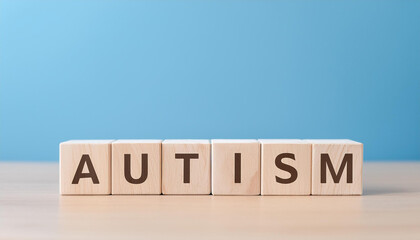 wooden cubes with word autism on wooden table against light blue background.