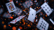 © nilanka - Playing cards falling in the air with fiery particles and dark background.