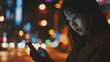 © VK Studio - A young woman engrossed in her smartphone, surrounded by the dreamy bokeh lights of a bustling city nightscape.