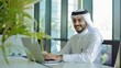 © The Little Hut - Portrait of young arab businessman inside office man typing on laptop smiling boss happy with results of financial success at workplace : Generative AI