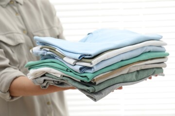 Wall Mural - Woman with stack of clean clothes indoors, closeup