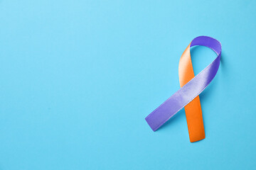 Wall Mural - World Psoriasis Day. Orange and orchid awareness ribbon as symbol of support on light blue background, top view. Space for text