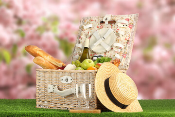 Canvas Print - Picnic basket with foods and wine on green grass outdoors